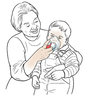 Kobieta trzymająca małego chłopca na kolanach i pomagająca mu oddychać przez maskę za pomocą inhalatora z dozownikiem.